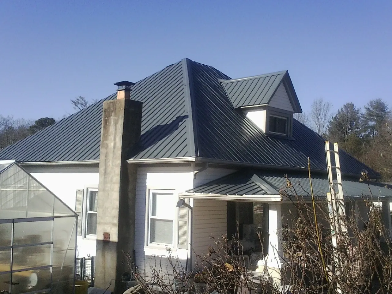Dark blue standing seam metal roof on a white farmhouse with dormer — Slate & Tile Roof Repair by Roofing Brothers in Lakeside Marblehead