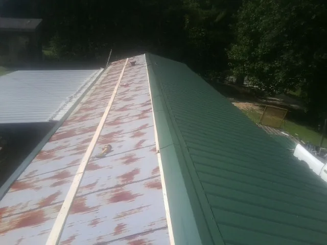 Old rusted panels beside newly installed green metal roofing — Wind Damage Roof Repair by Roofing Brothers in Lakeside Marblehead