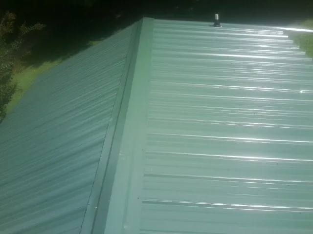 New green metal panels meeting at the ridge of a roof — Flat Roof Repair work by our crew in Lakeside Marblehead