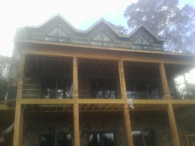 Dormers and porch framing on a large log home under construction — Roof Coating work by our crew in Lakeside Marblehead