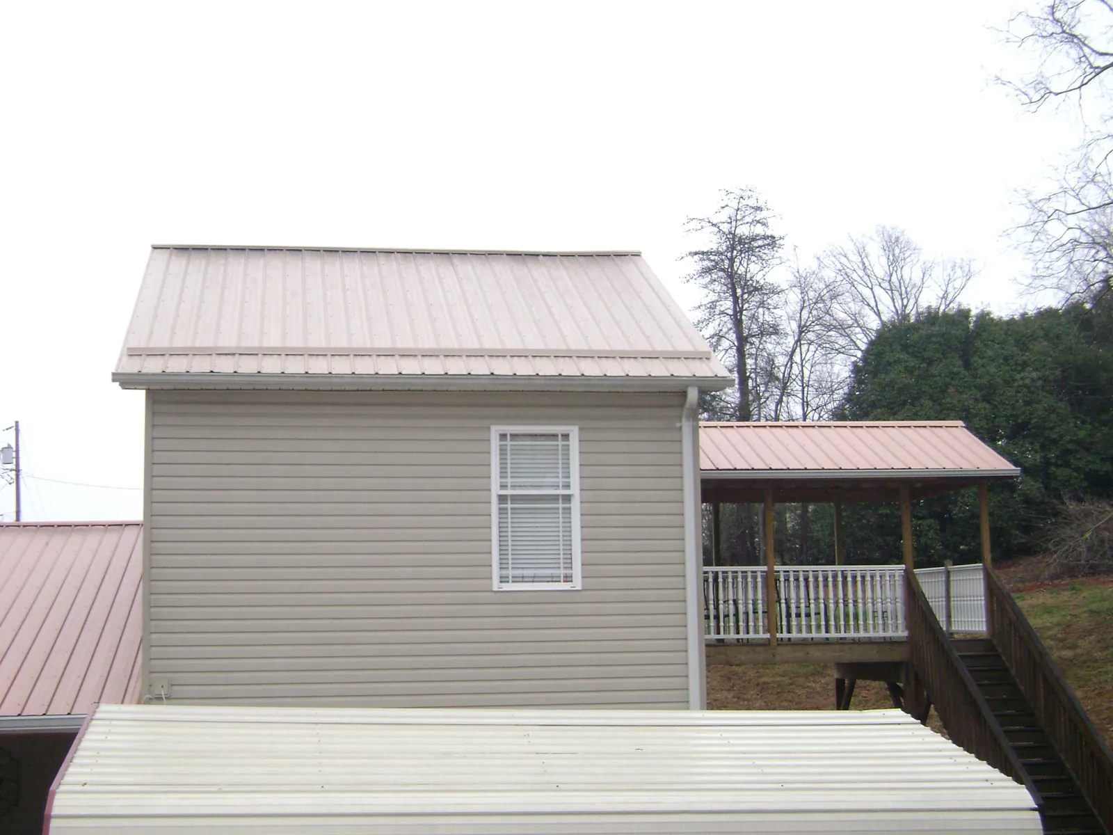 Tan metal roofs on a two story addition and attached porch, from a Roof Replacement job in Lakeside Marblehead