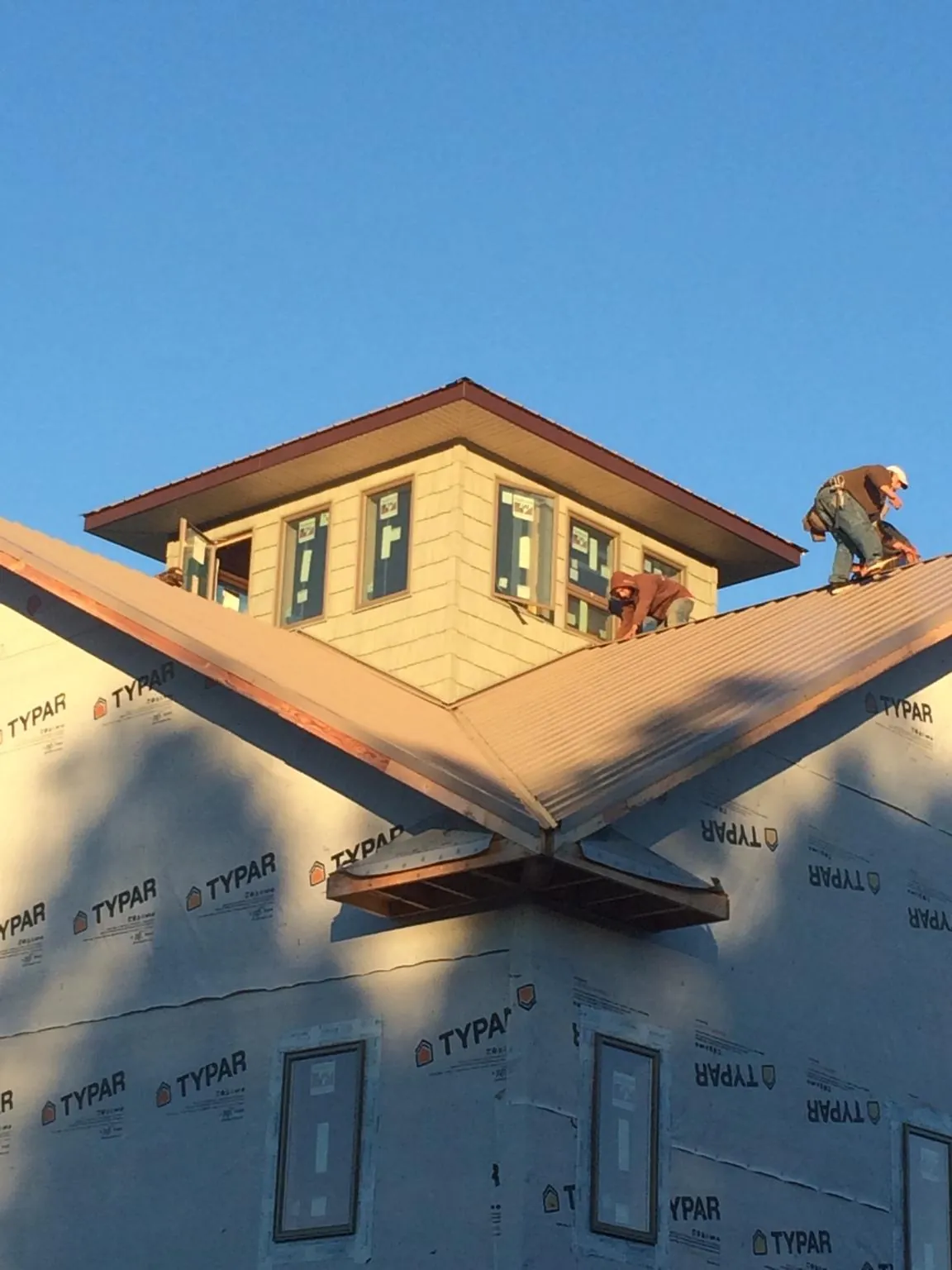 Roofers working around a rooftop cupola on a new metal roof at sunset — Roof Waterproofing in Lakeside Marblehead by Roofing Brothers